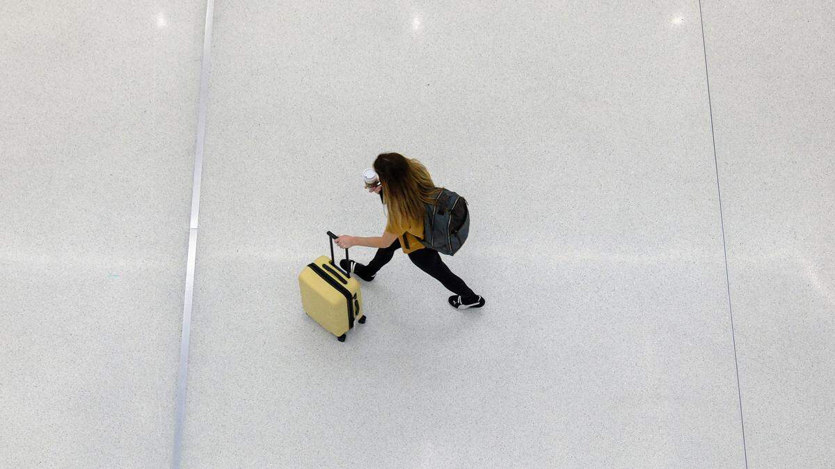 A woman with a suitcase and backpack makes her way in Terminal B at LaGuardia airport in the Queens borough of New York City