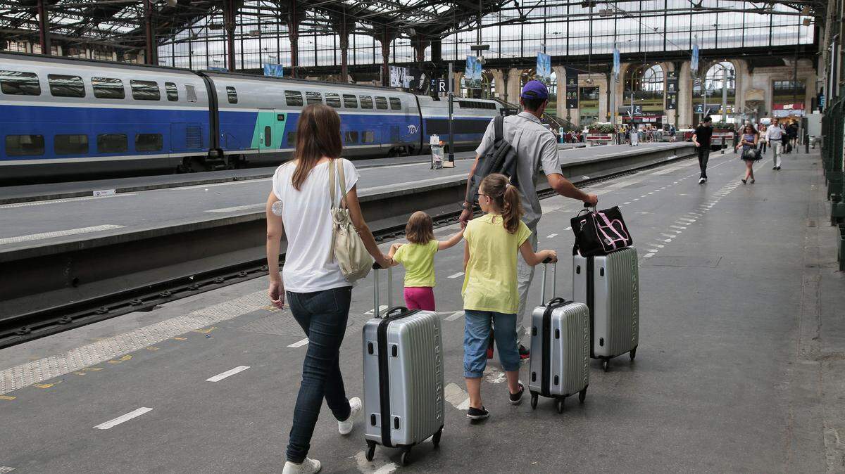 Passengers walk through the Gare de Lyon train station with suitcases.