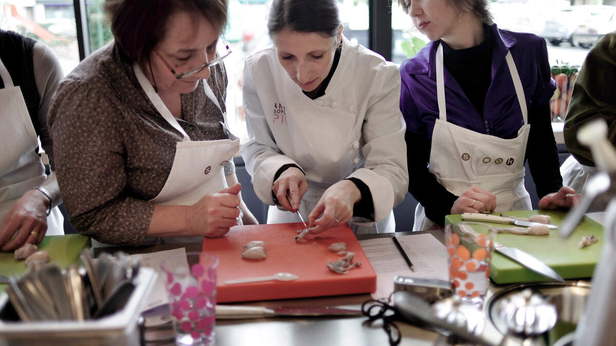 A chef explains how to remove the bones of frog legs during a French cooking class.