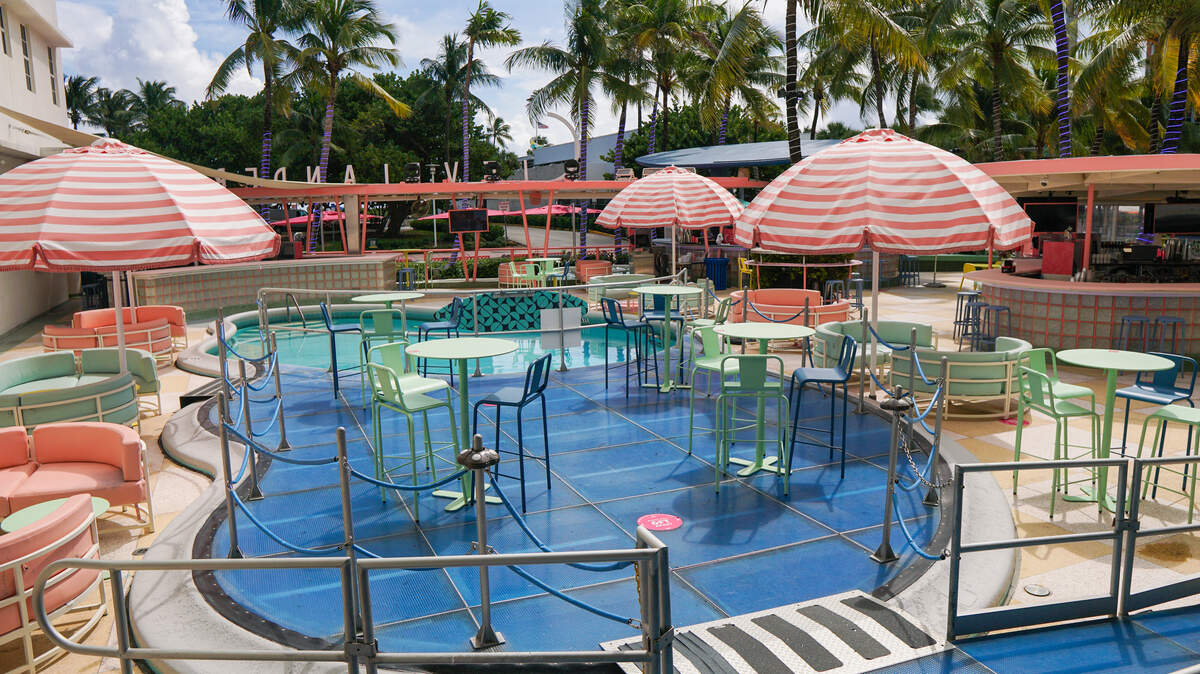 Dining tables and chairs with umbrellas on an outdoor poot deck.