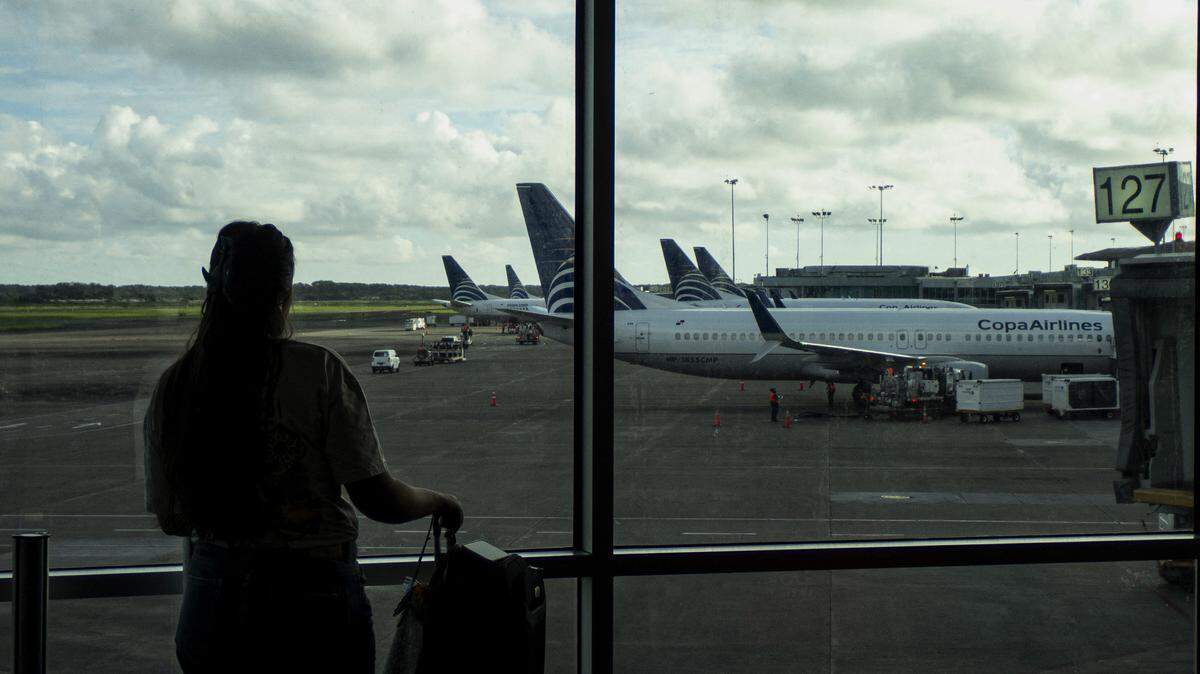 A woman looks at the planes out the window of an airport.
