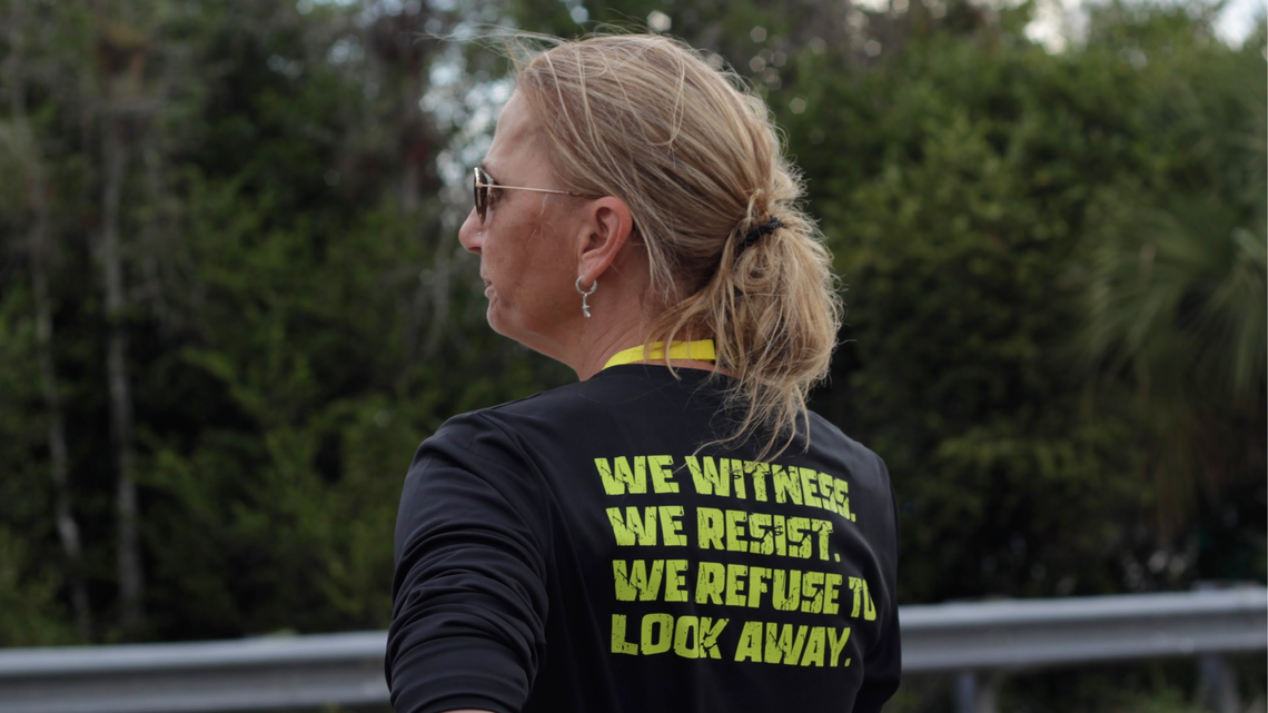 Jenn Bakowski, one of the main organizers behind Joyful Resistance, watches a car pass by at Alligator Alcatraz on Sunday, March 1.