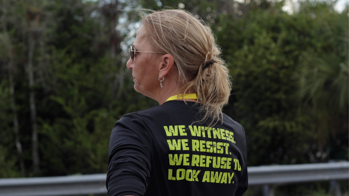 Jenn Bakowski, one of the main organizers behind Joyful Resistance, watches a car pass by at Alligator Alcatraz on Sunday, March 1.