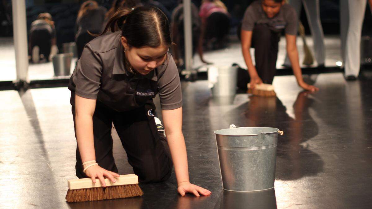 Mia Lowe pretends to scrub the floor during a rehearsal for “Annie Jr.” in the Coral Springs Charter School theater.