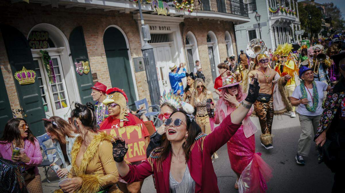 A group of people in costumes taking part in Mardi Gras Day festivities along Bourbon Street in New Orleans