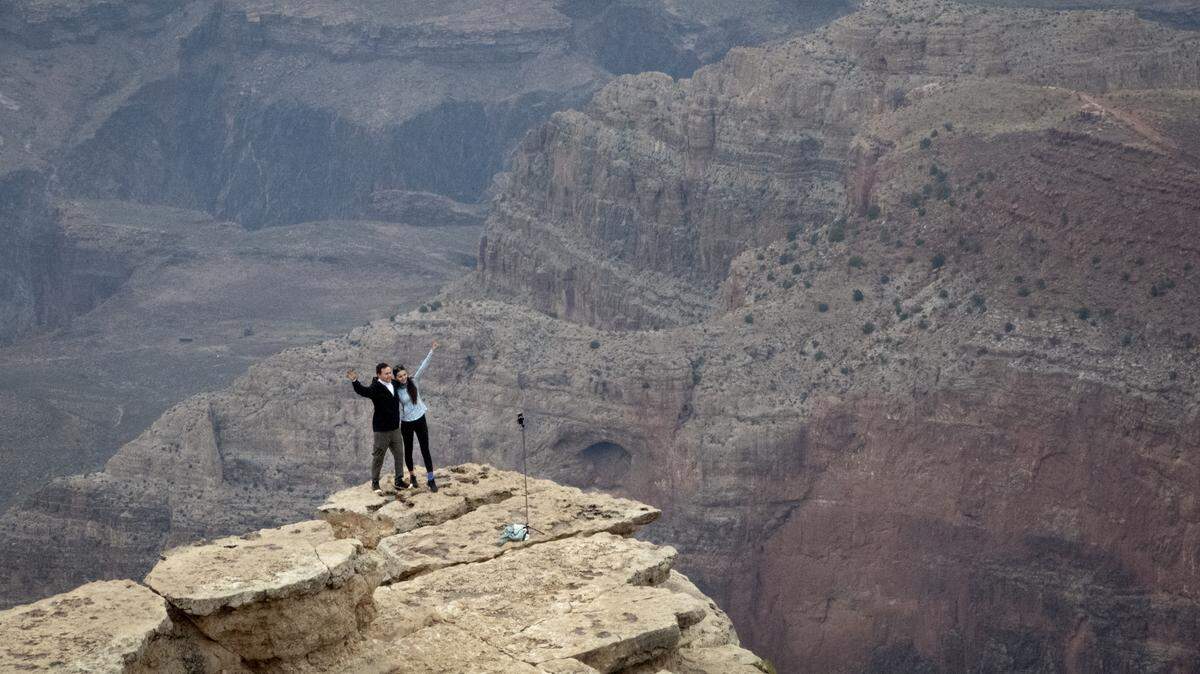 A couple takes pictures from an outcropping as smoke from the Dragon Bravo fire fills the Grand Canyon in Grand Canyon, Arizona.