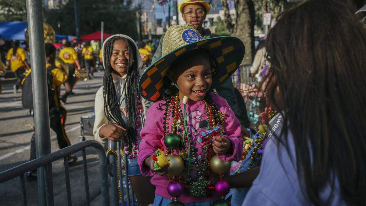 Children smile while wearing beads and taking part in the Mardi Gras parade in New Orleans, Louisiana