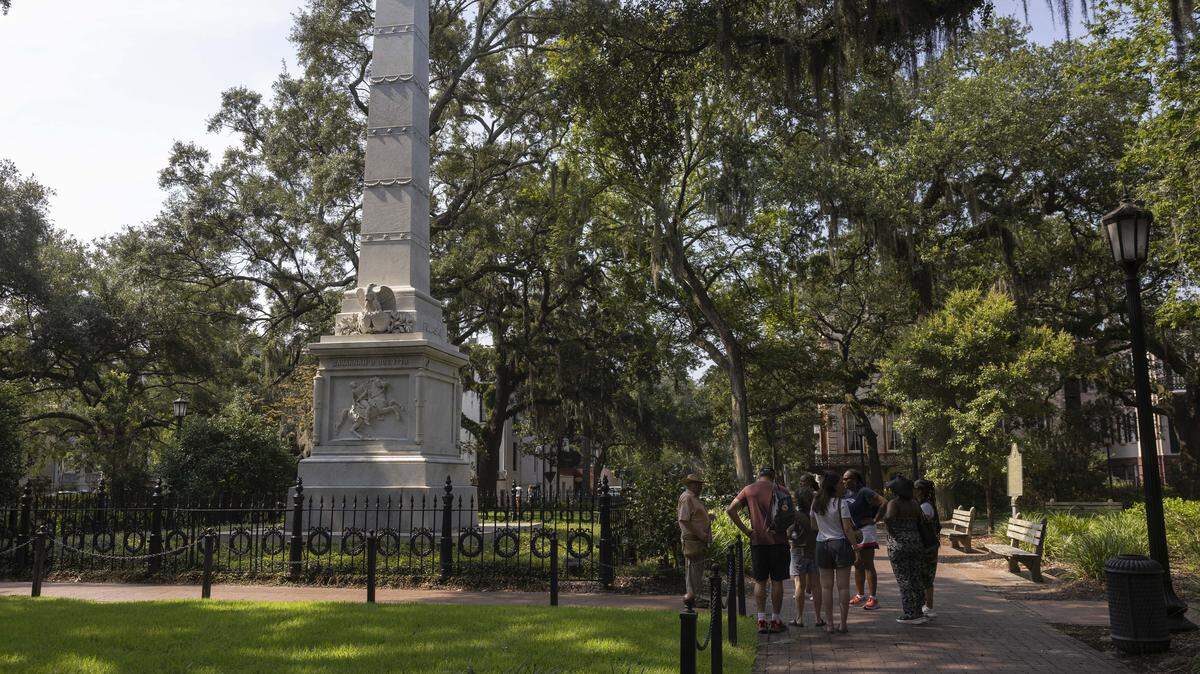 People participate in a walking tour past a monument in Savannah, Georgia