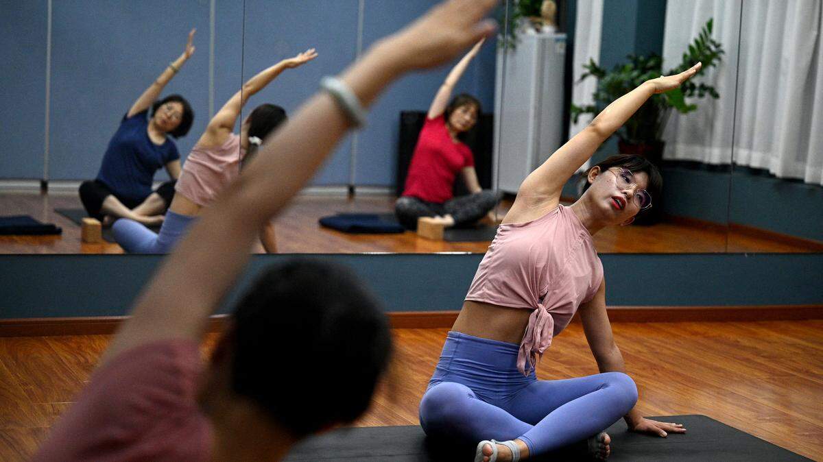 A yoga instructor stretching with students at a gym