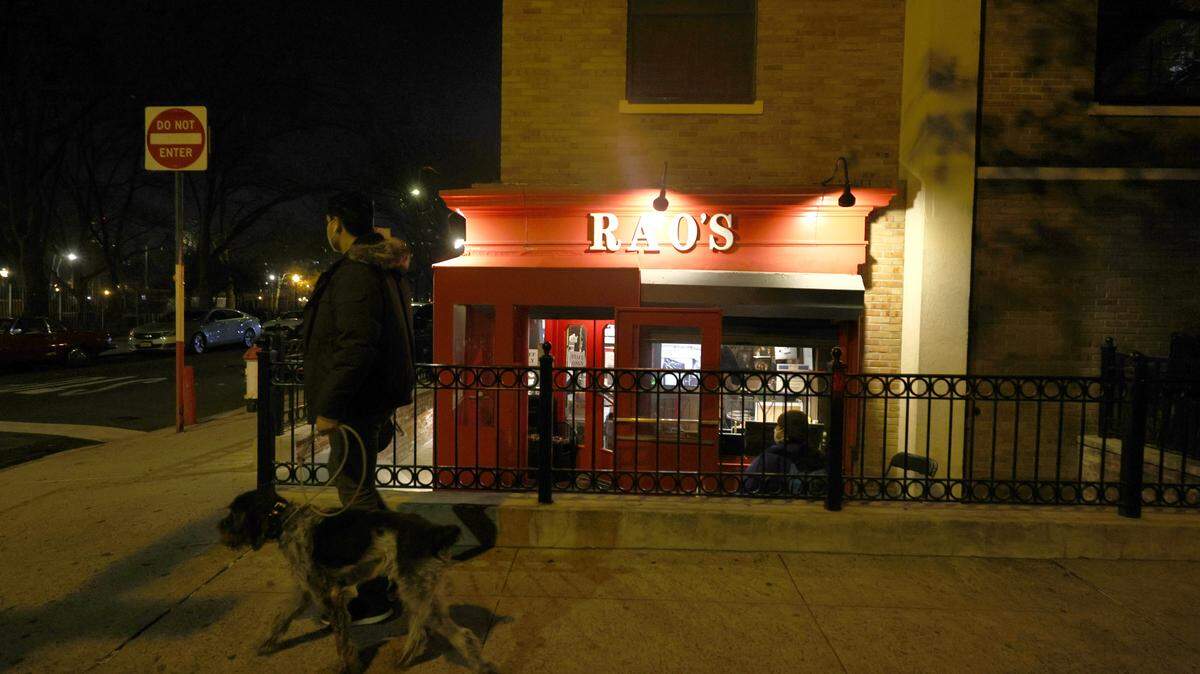 A man walks his dog past Rao’s restaurant in East Harlem.