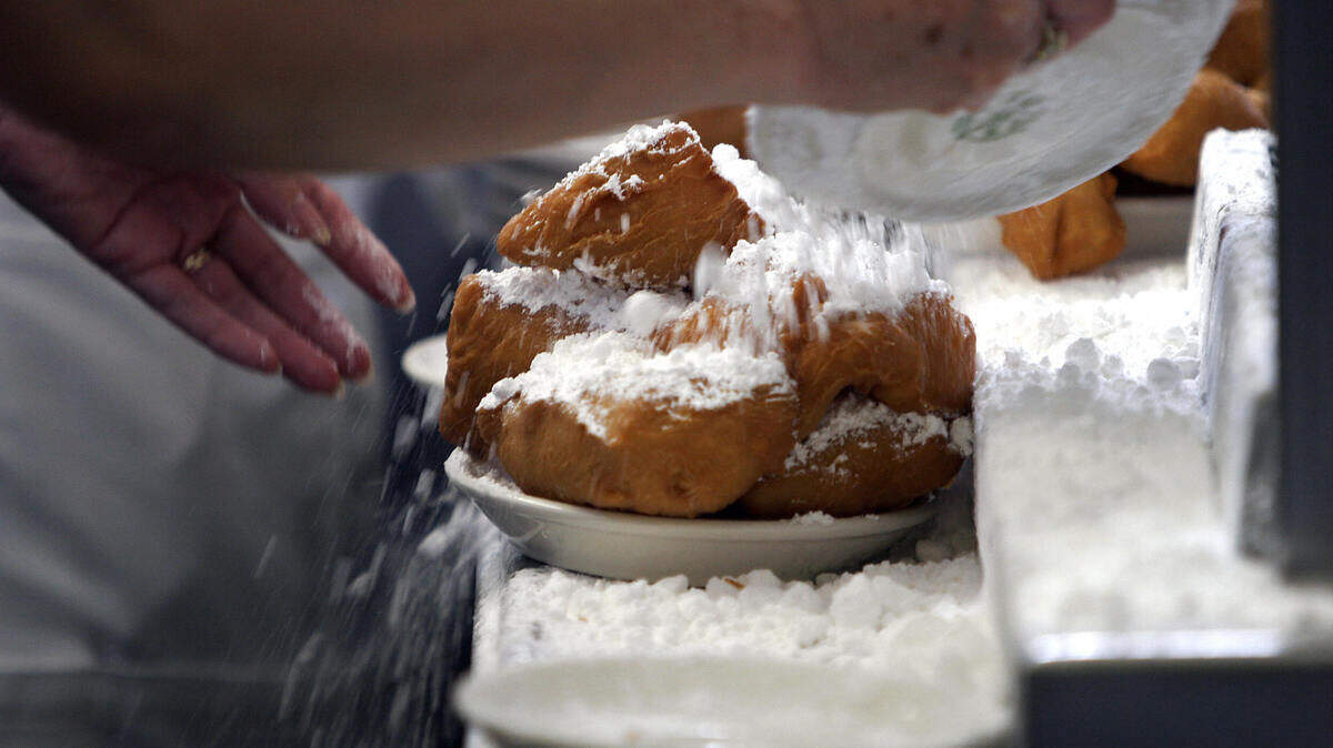 Waitresses prepare beignets by covering them with powdered sugar, in the kitchen of Cafe du Monde in New Orleans.