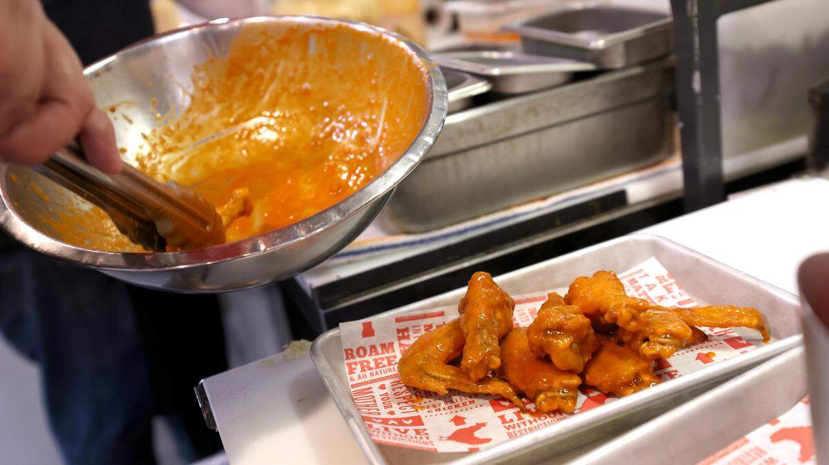 A cook prepares Buffalo chicken wings.