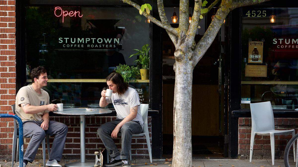 Two men drink coffee outside of Stumptown Coffee Roasters in Portland, Oregon.