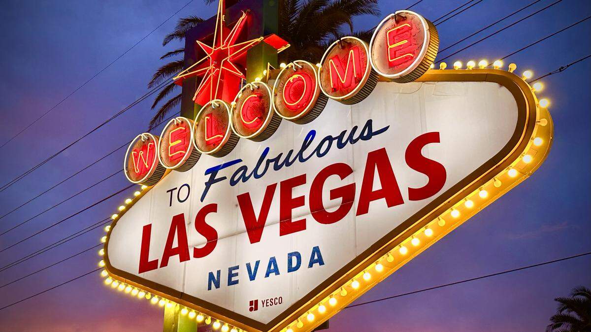 A sideways view of the sign reading “Welcome to Fabulous Las Vegas Nevada” with a sunset in the background.