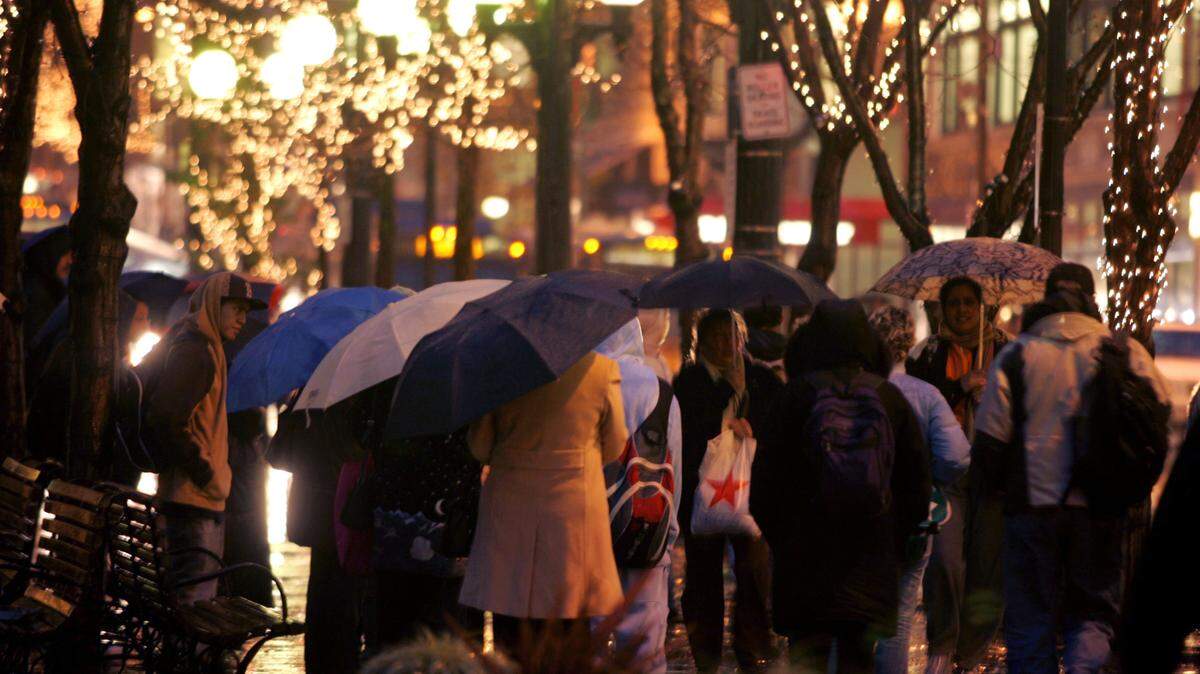 Some commuters carry umbrellas as they wait for buses in Rainier Square on 4th Avenue during evening rush hour in Seattle, Washington.
