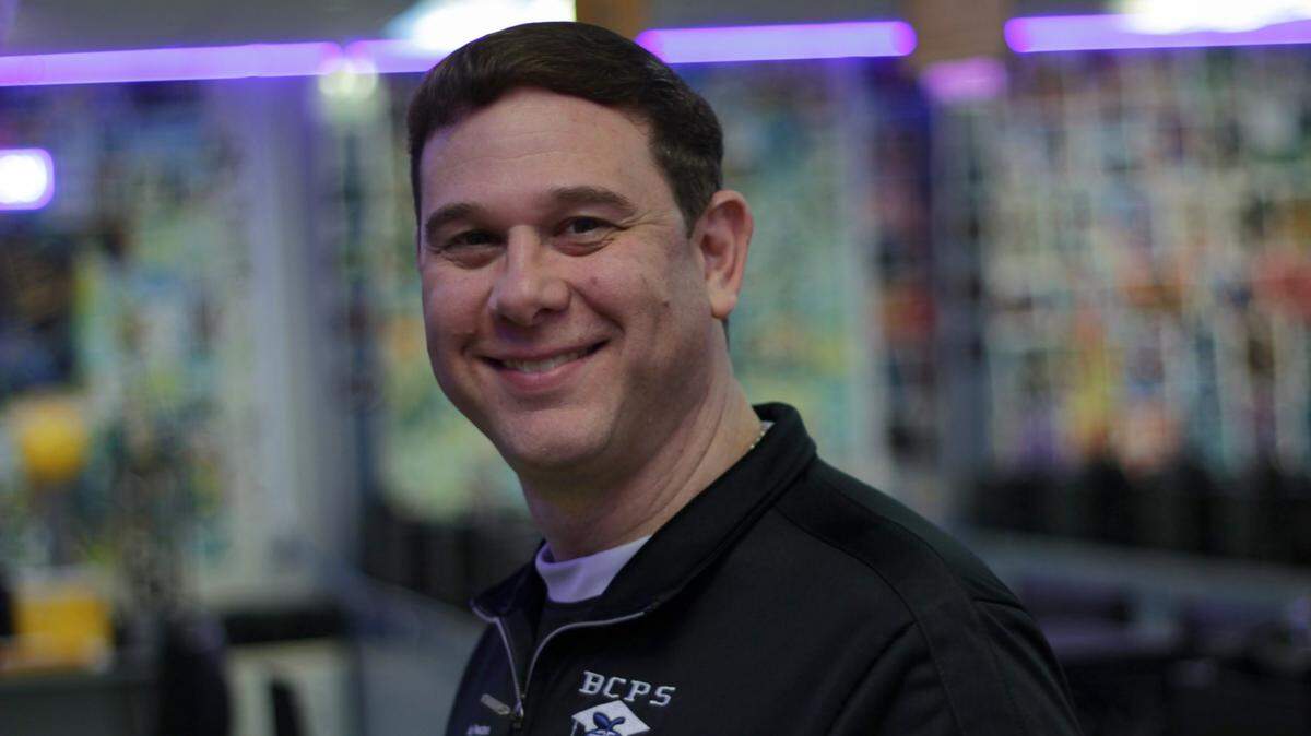 Jason Freedman stands for a portrait in his classroom, which is decked out with comic book printouts, colorful lights and awards won by his e-sports and business competition teams.