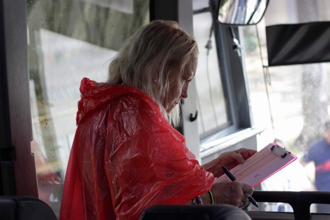 Katherine Donovan examines a list on her clipboard while waiting for more passengers to board the bus bound for Alligator Alcatraz on March 1.