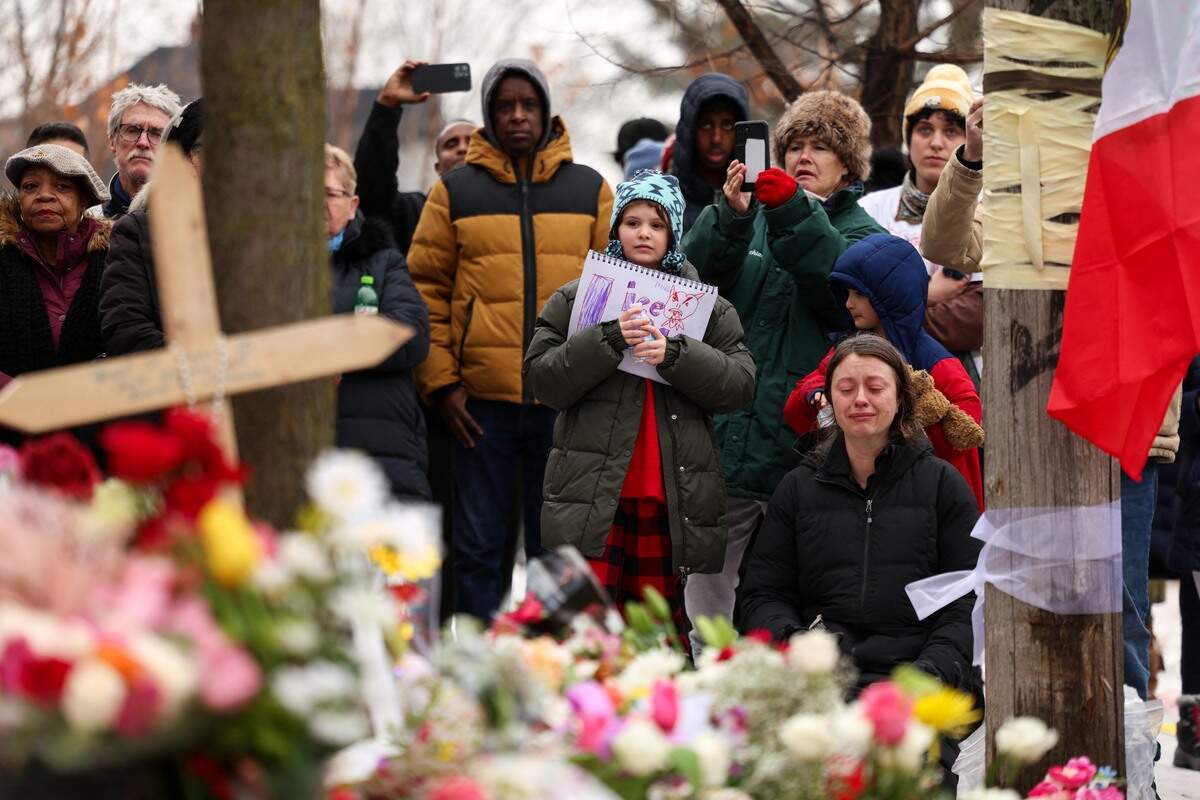 People gather at the street where 37-year-old Renee Nicole Good was shot and killed at point blank range on by a U.S. Immigration and Customs Enforcement agent as she apparently tried to drive away from agents who were crowding around her car in Minneapolis.