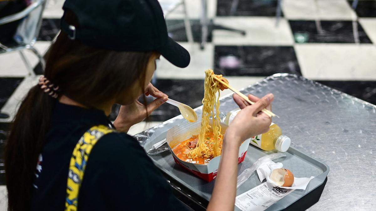 A woman eats noodles for lunch alone at a table.