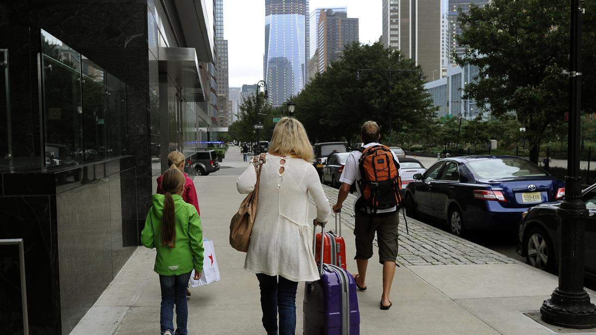 People leave the Ritz Carlton Hotel in Battery Park in New York City with their suitcases.
