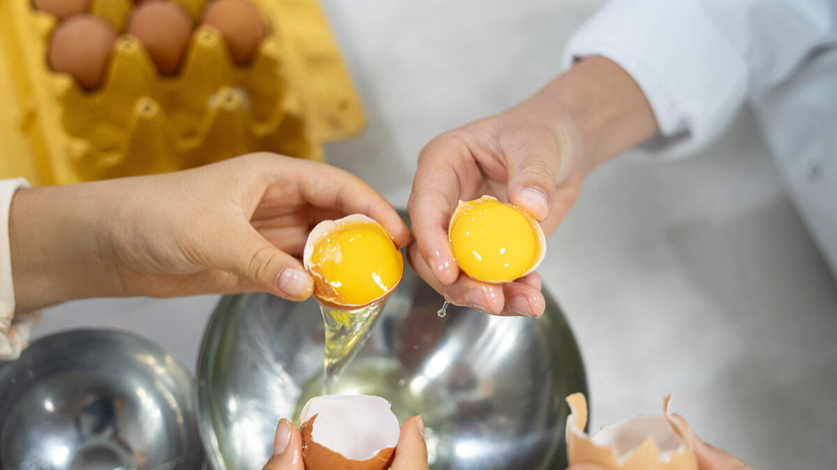 Two people separating egg whites from yolks to make mayonnaise during a cooking class.