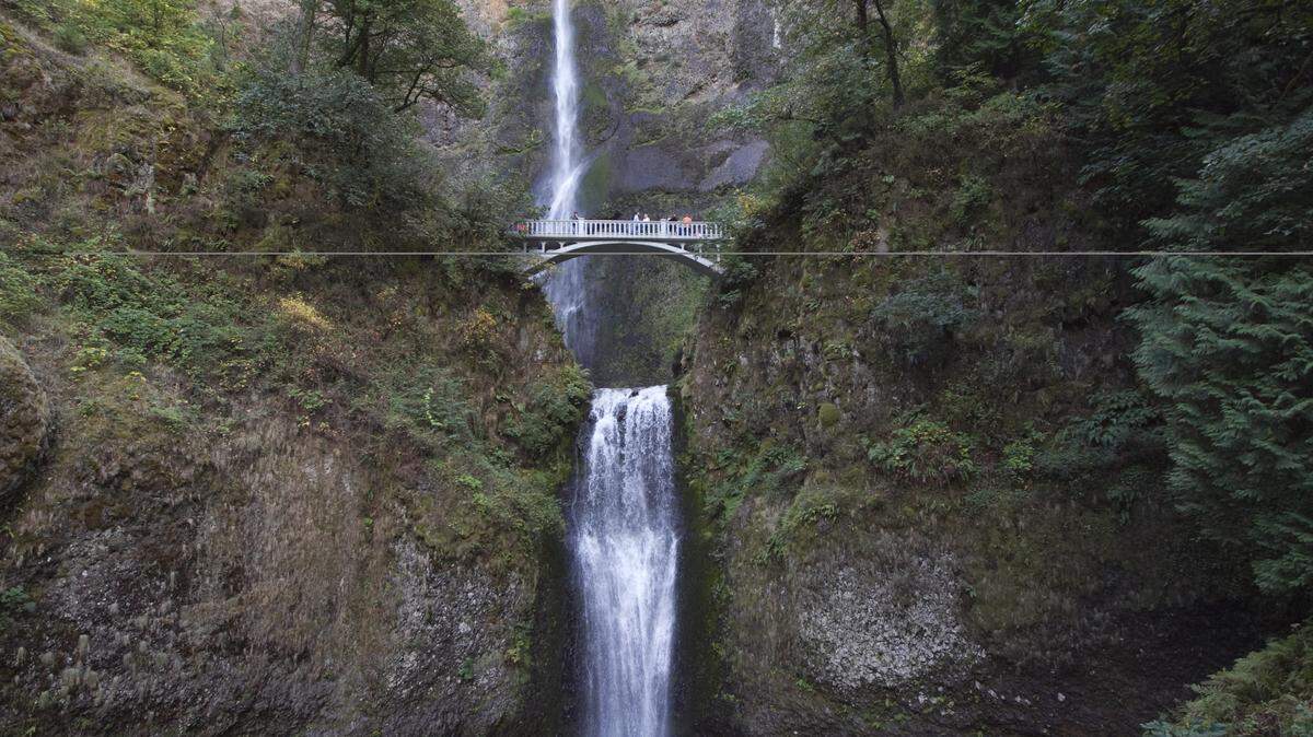 Visitors on a bridge admire the Multnomah Waterfalls, in the Columbia River Gorge National Scenic Area in Multnomah Falls, Oregon.