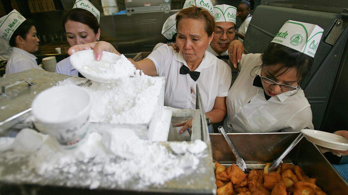 Waitresses prepare beignets covered with powdered sugar at Cafe du Monde, one of the most popular tourist spots in New Orleans.