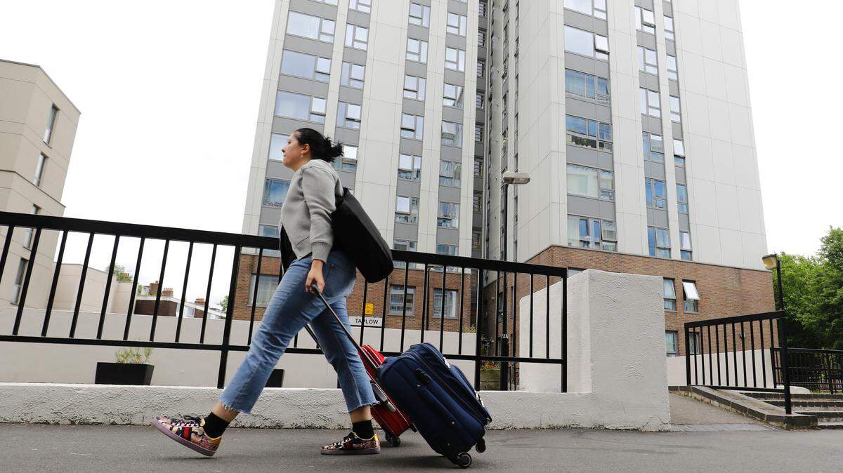 A woman with suitcases leaves Taplow Tower residential block on the Chalcots Estate in north London.