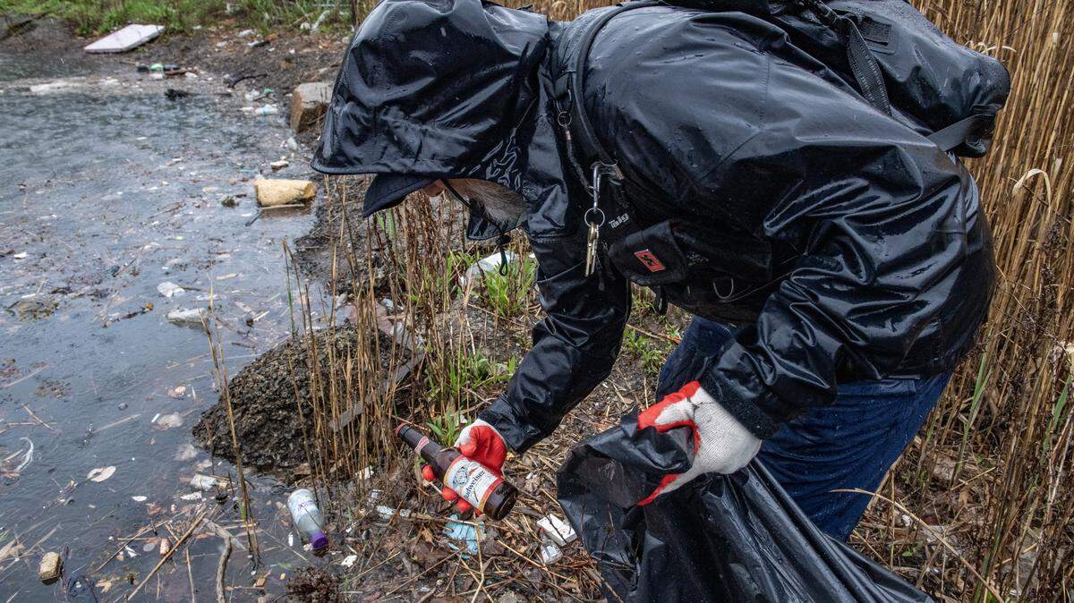 A man works to clean up trash from a salt marsh.