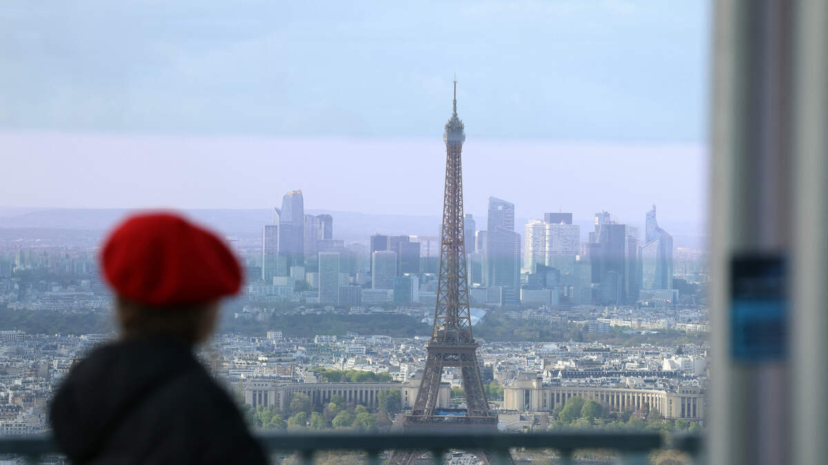 A woman looks out towards the Eiffel Tower and La Defense from the observation gallery on the top of the Tour Montparnasse (Montparnasse Tower) in Paris.