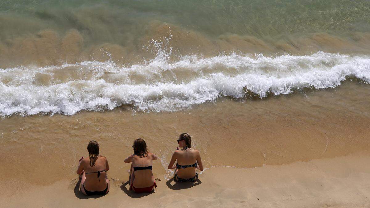 Women sit on the sand on Saint Joseph beach in Ajaccio, on the French Mediterranean island of Corsica.