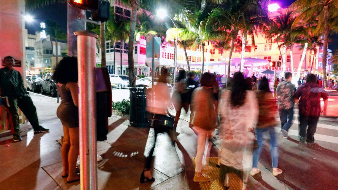 Group of people crossing the street in Miami with palm trees in the background
