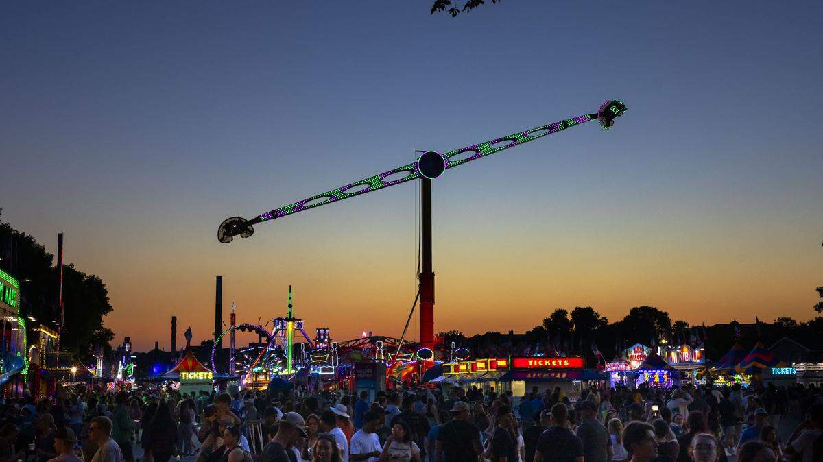 Fairgoers enjoy the Minnesota State Fair as the sun sets behind them.
