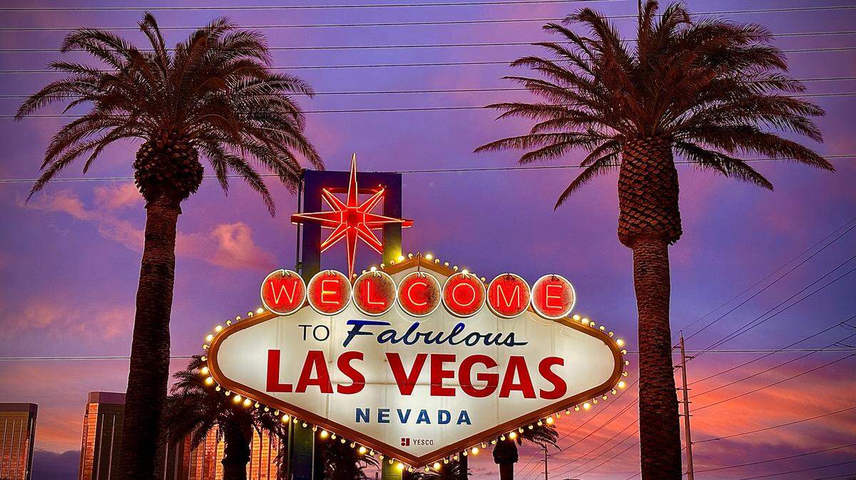 The iconic sign reading “Welcome to Fabulous Las Vegas Nevada” with palm trees on either side and a sunset in the background.