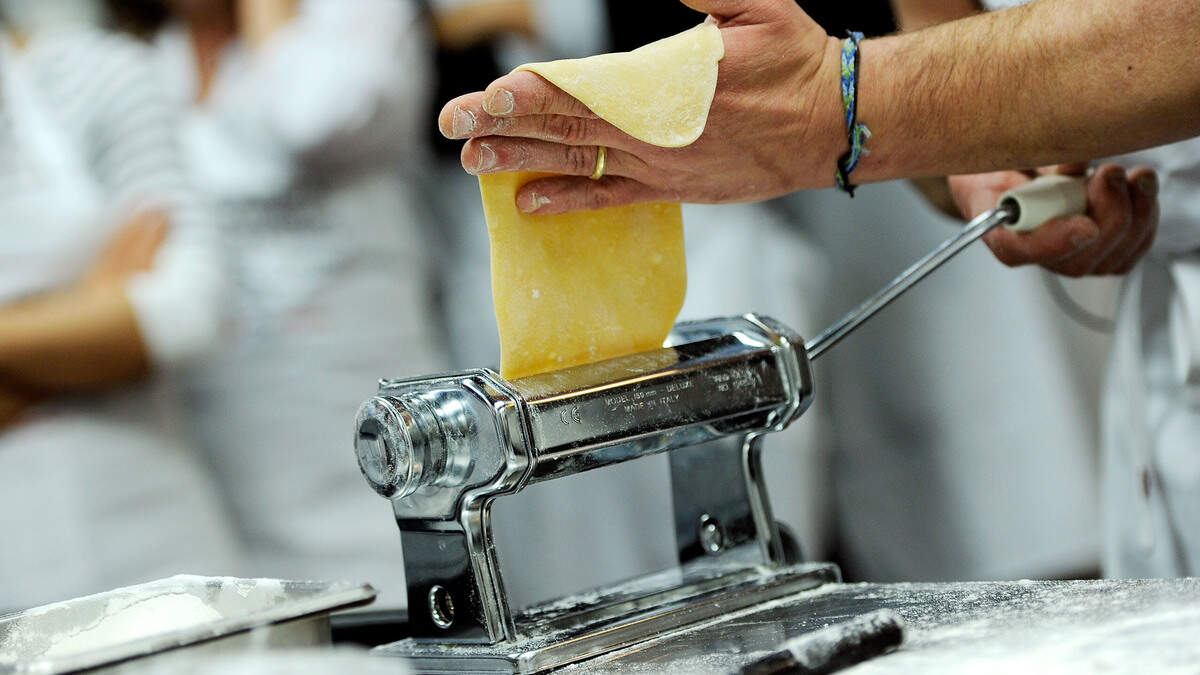 A chef rolls out pasta dough.