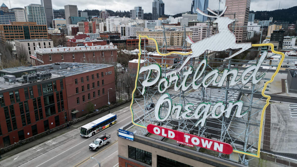 An aerial image shows the White Stag neon sign as vehicles cross the Willamette River in downtown Portland, Oregon.