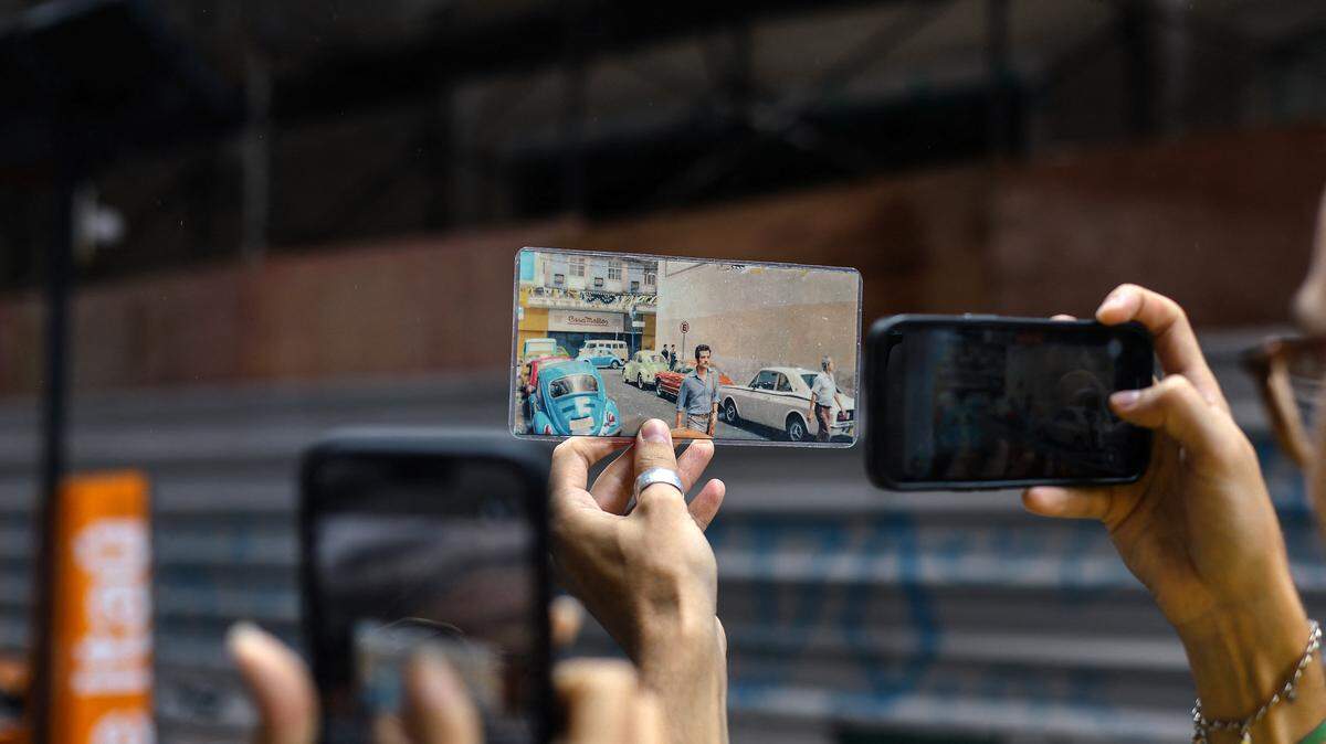 A tourist holds a photo showing a scene from a film against the backdrop of where it was filmed during a guided tour.