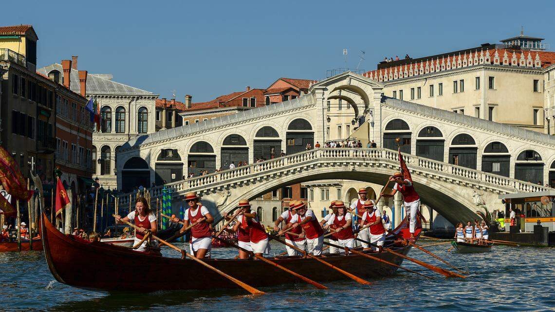 Rowers in gondolas on the Grand Canal, close to Rialto bridge in Venice.