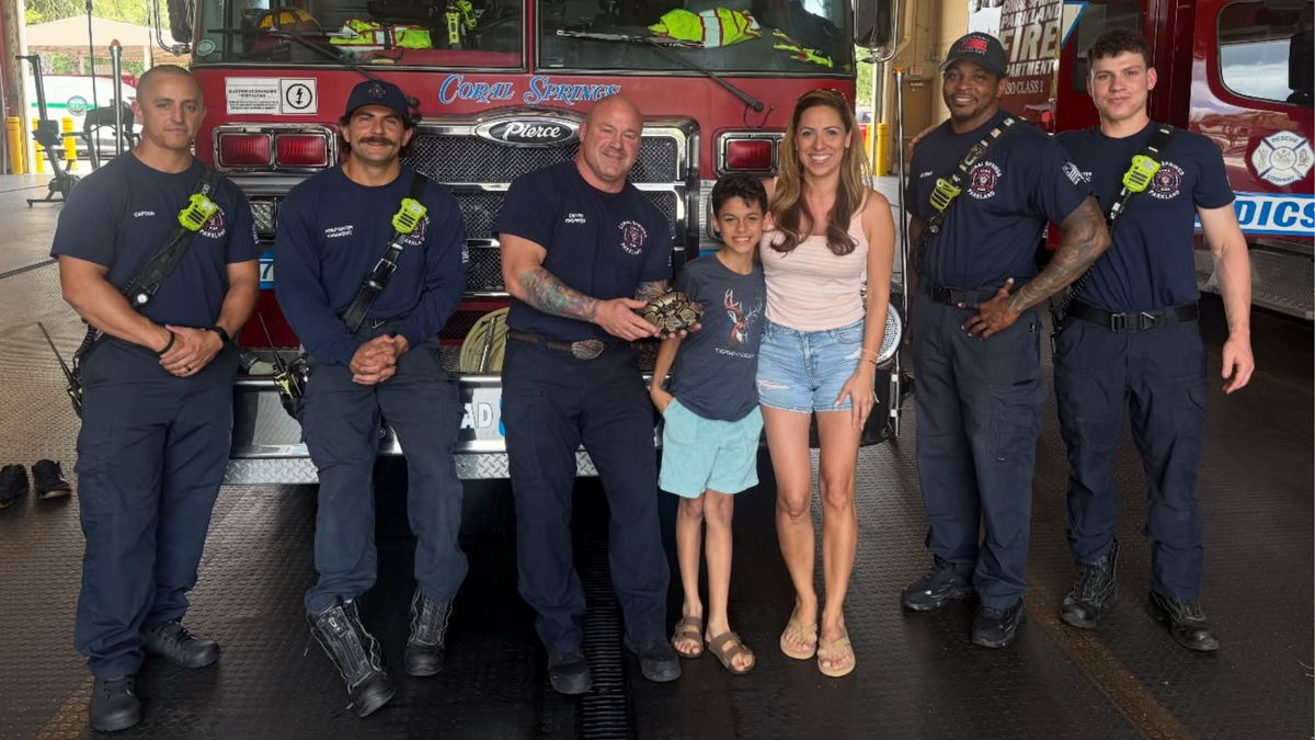 Coral Springs Fire Department staff and the snake’s owners pose for a celebratory photo after the python’s rescue.
