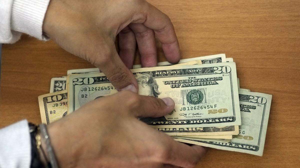 Two hands holding a stack of United States 10 and 20 dollar bills.