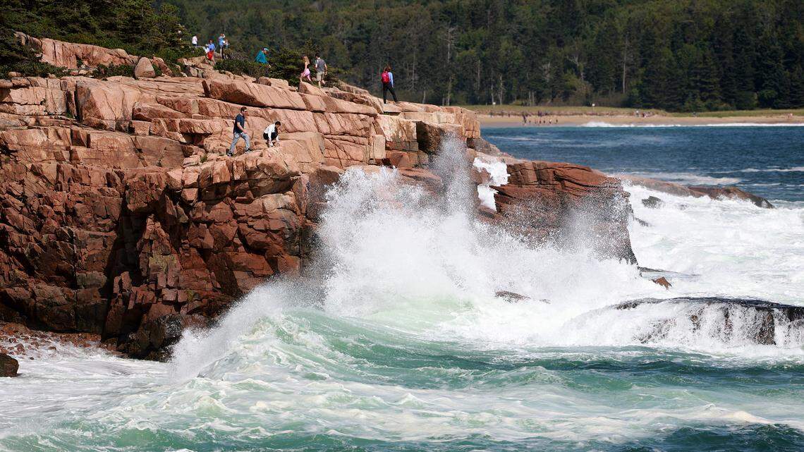 People watch as waves break ashore in Acadia National Park.