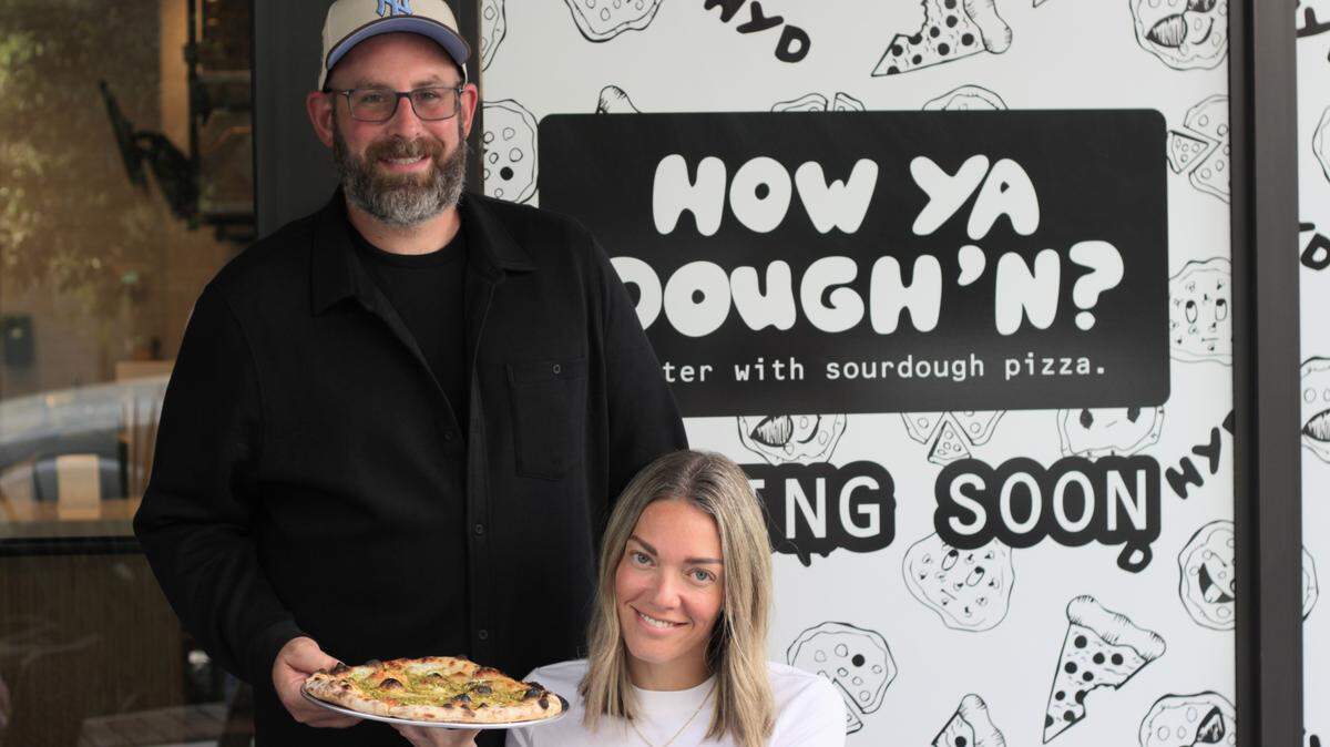 Garrett and Gabby Goodman pose in front of the sign for their restaurant, How Ya Dough’n, in Coral Springs’ Cornerstone complex on April 6.