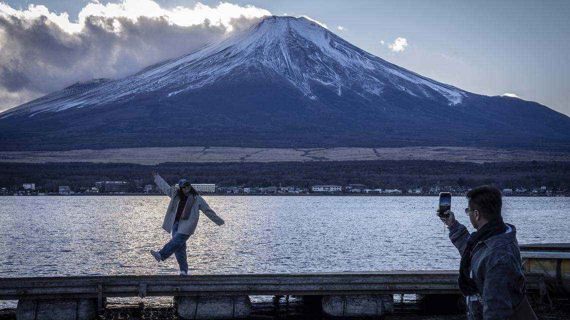 People take photographs with Mount Fuji at Lake Yamanakako in snow.