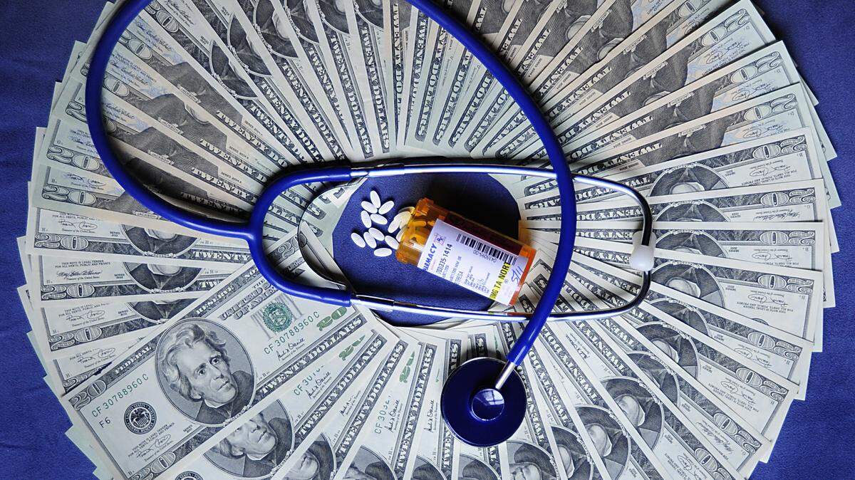 A ring of twenty US dollar bills with a bottle of prescription drugs and a stethoscope.