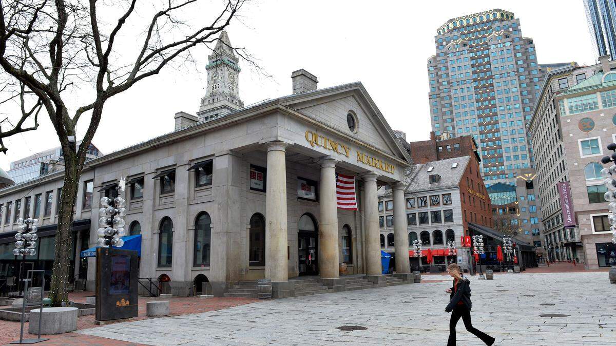 A woman walks by the outside of Quincy Market at Faneuil Hall Marketplace