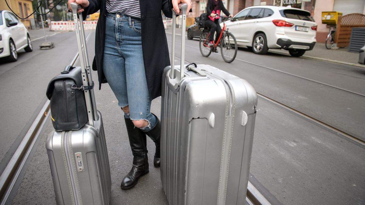 A woman pulls to suitcases down the road.