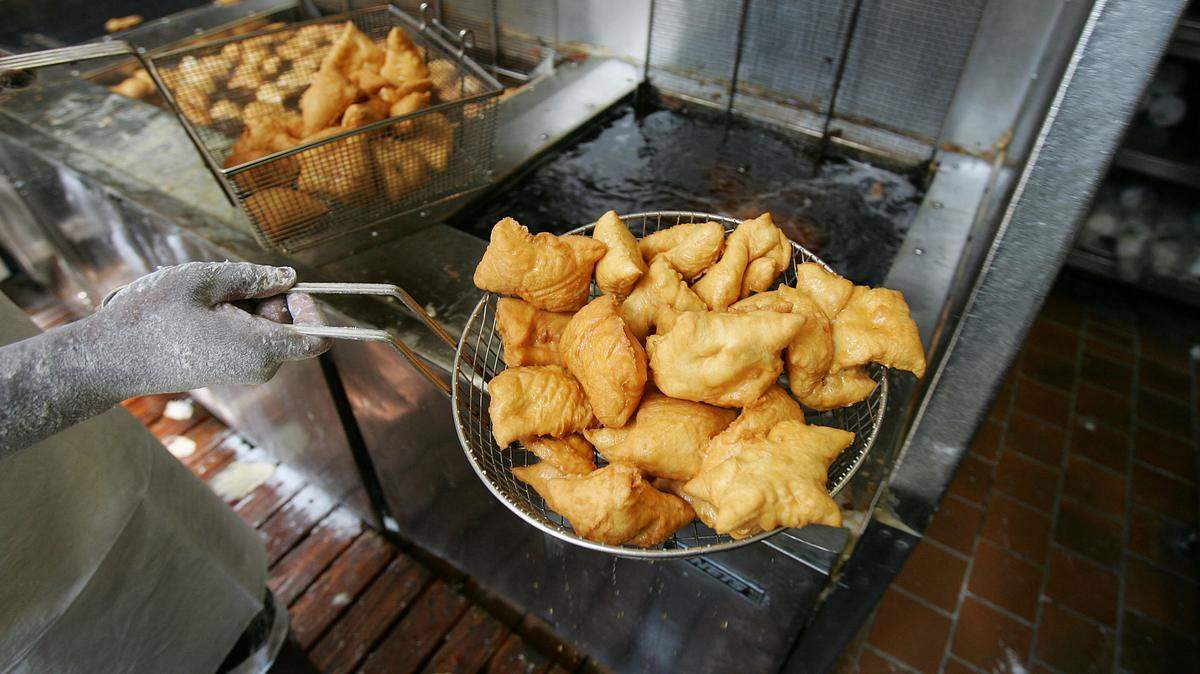 A cook removes beignets from a deep fryer in the kitchen of Cafe du Monde, one of the most popular tourist spots in New Orleans, famed for their coffee and beignets.