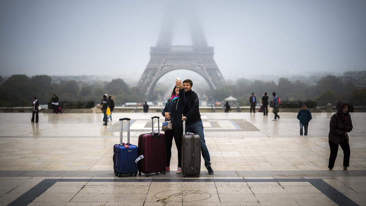 Tourists take a selfie on the Parvis des droits de l’homme square, in front of the Eiffel tower in Paris.