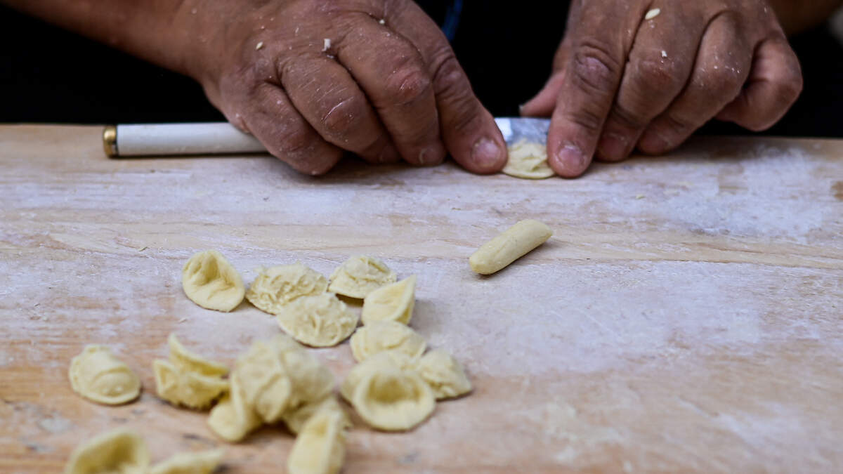 A woman prepares homemade orecchiette pasta.