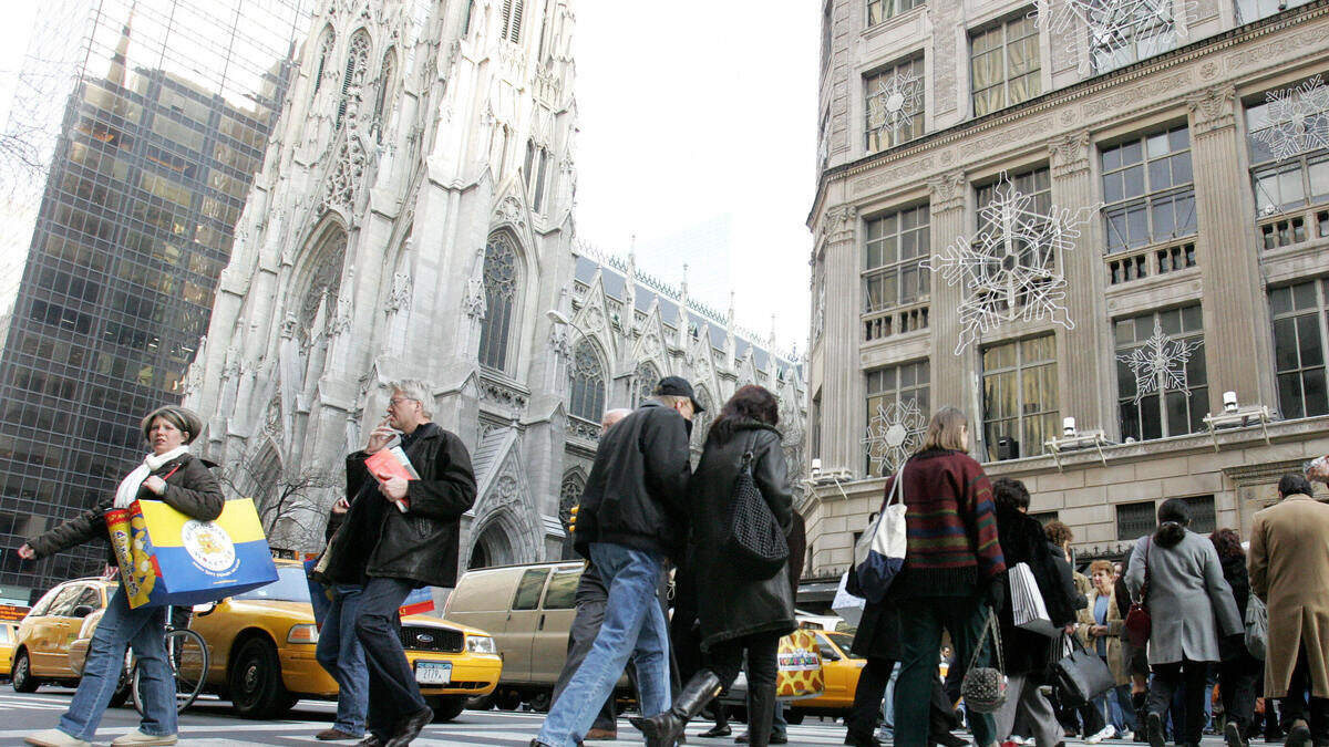 Holiday shoppers carry bags as they walk up Fifth Avenue in Manhattans